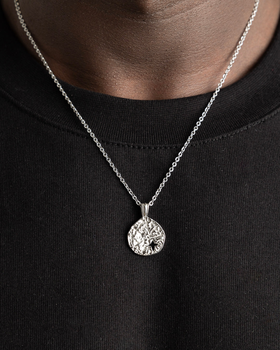 Textured circular pendant with star cutout on a silver chain from the MIST SILVER NECKLACE