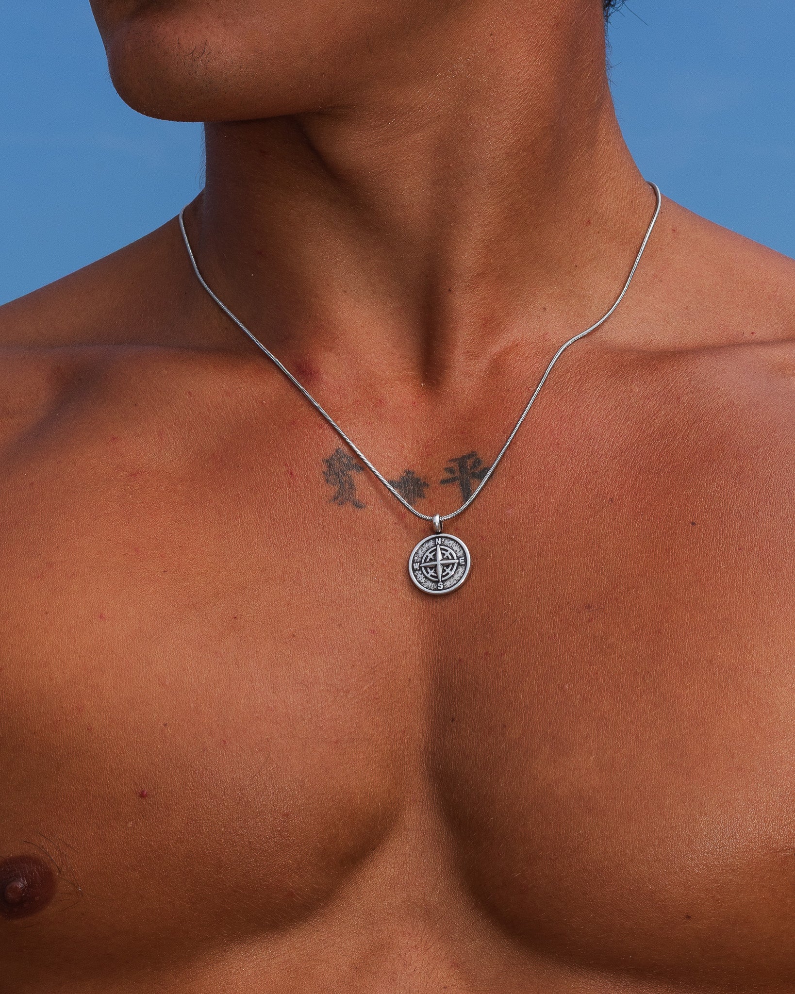 Mojave silver necklace close-up with compass pendant resting on the chest.