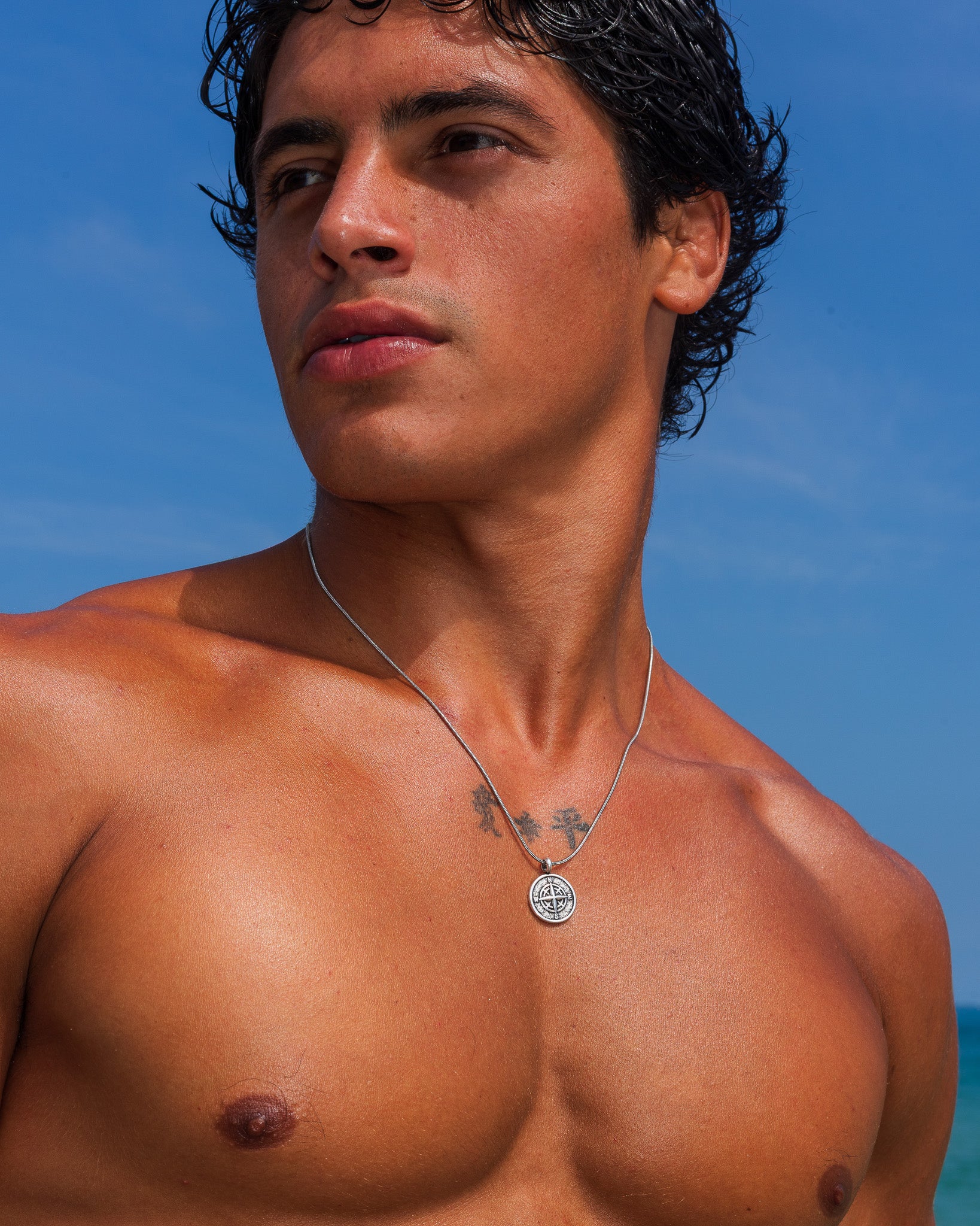 MOJAVE SILVER NECKLACE with round medallion pendant on a tattooed chest at the beach
