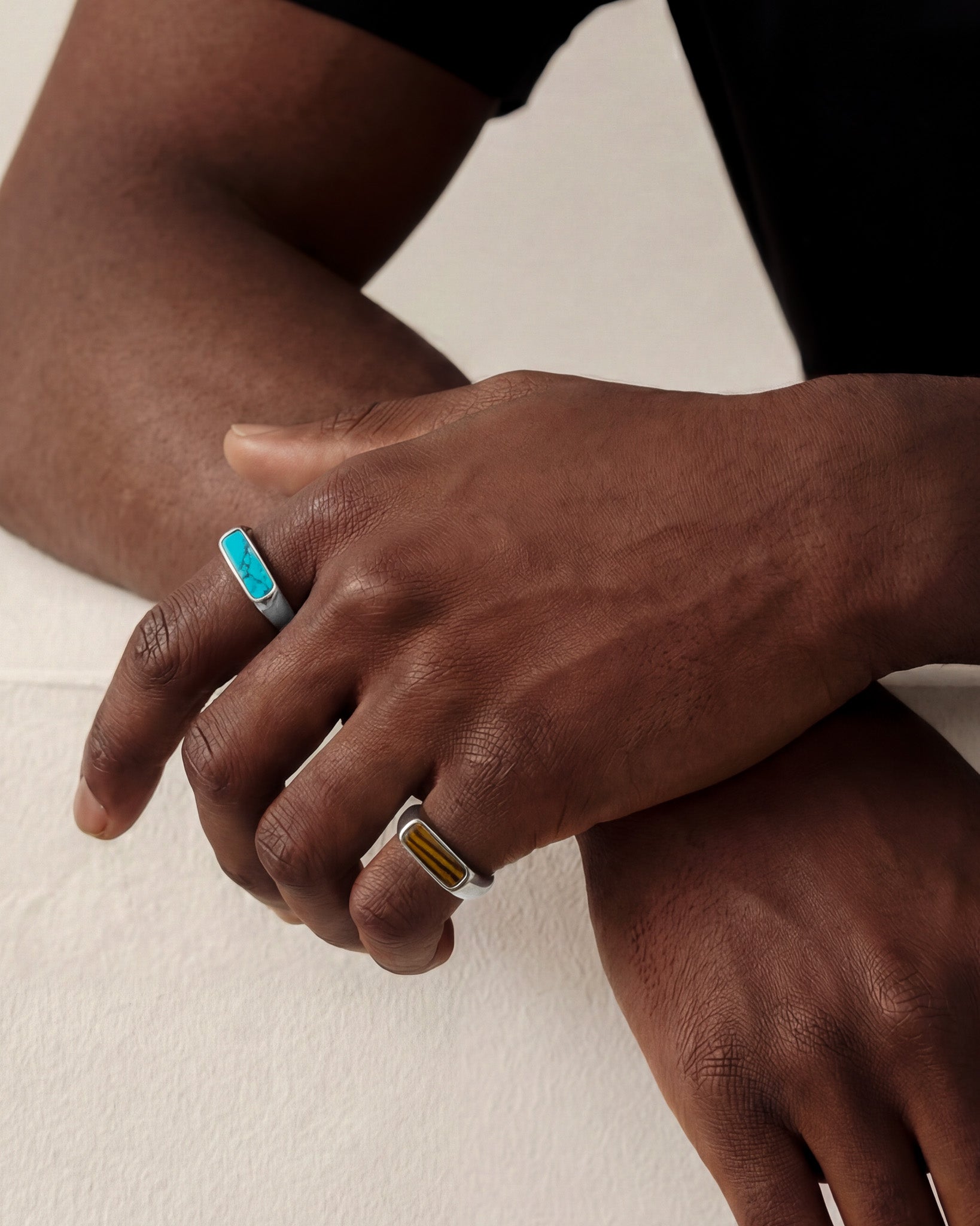Two NOVA Silver Rings worn on a hand featuring turquoise and tiger eye inlays