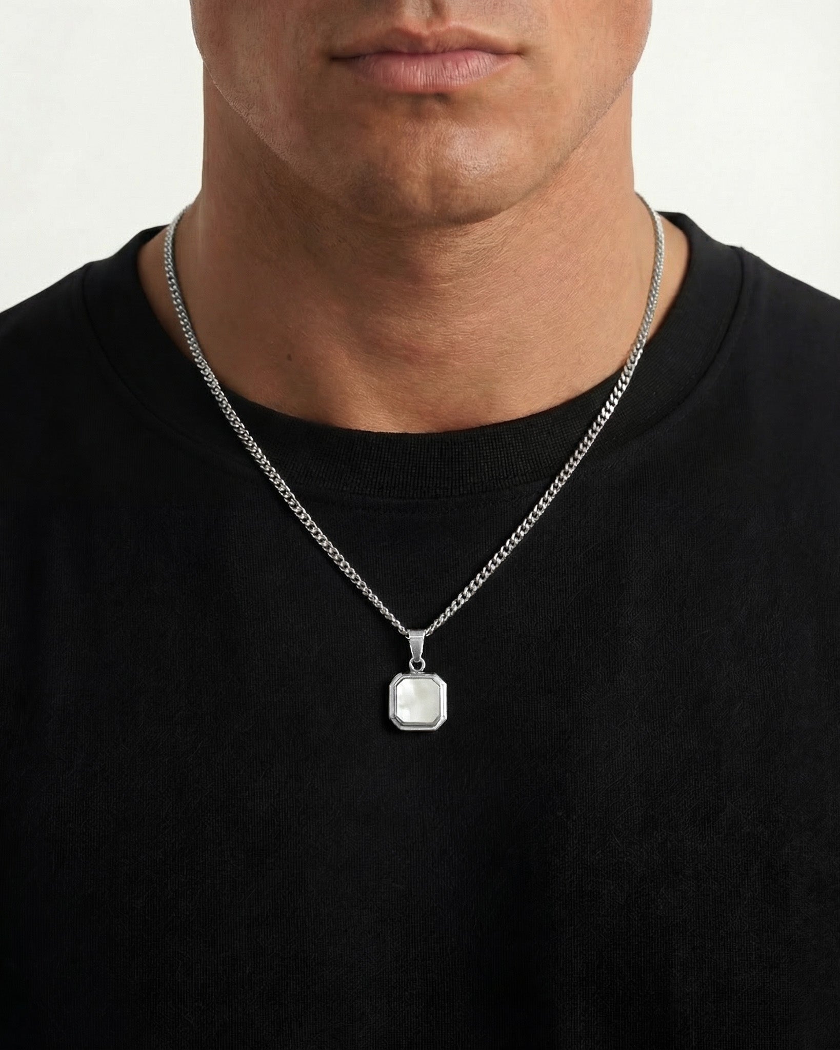 Model wearing NOVA Silver Necklace with a thick curb chain and square framed pendant on a black shirt