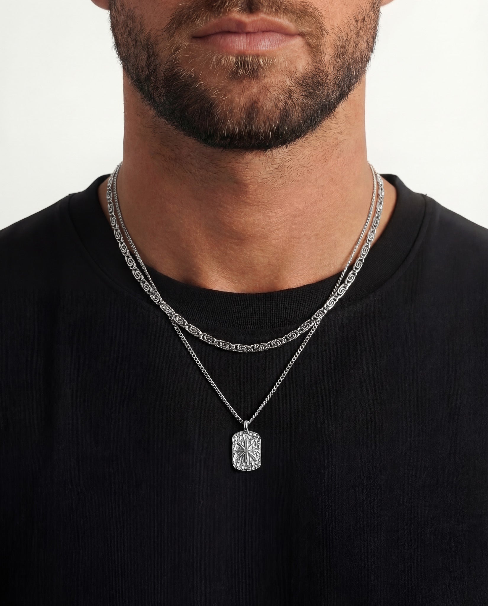 NUSA silver chain with engraved rectangular pendant on layered chains against a black shirt