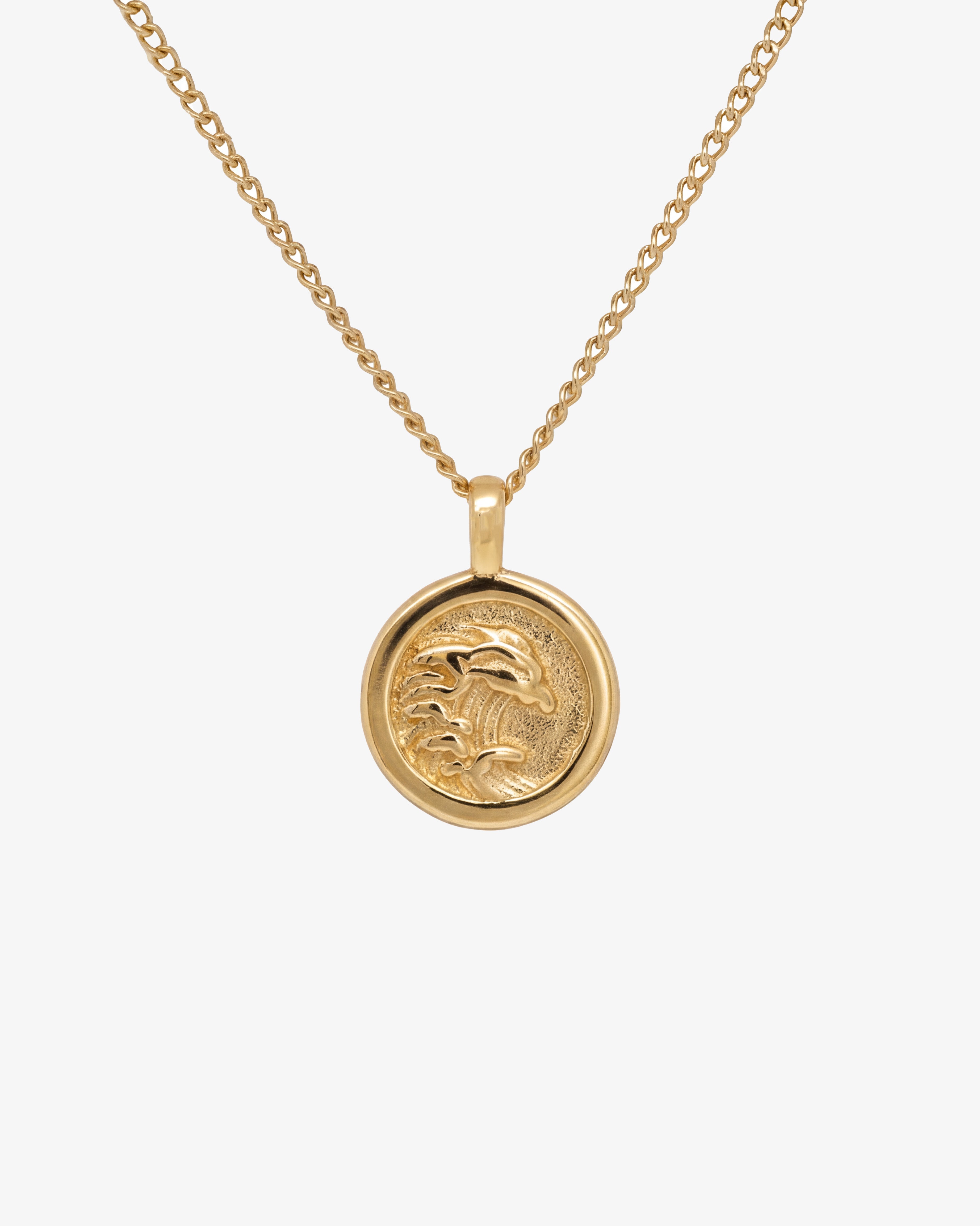Gold OAHU necklace with a round palm tree pendant on a pale background