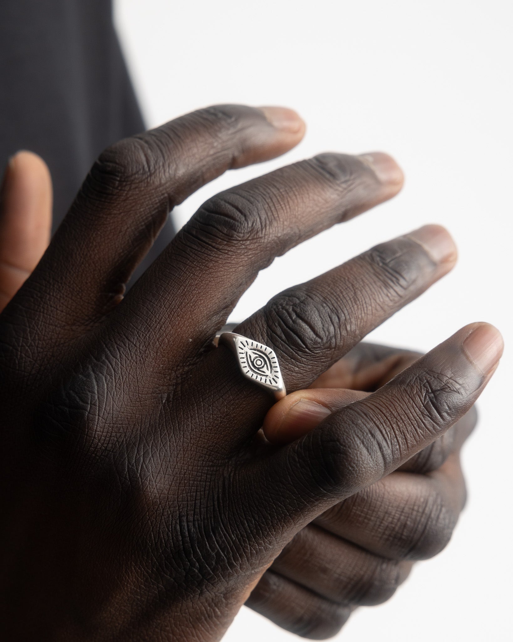 Hand wearing the ORUS silver ring with the eye motif on a slim band.