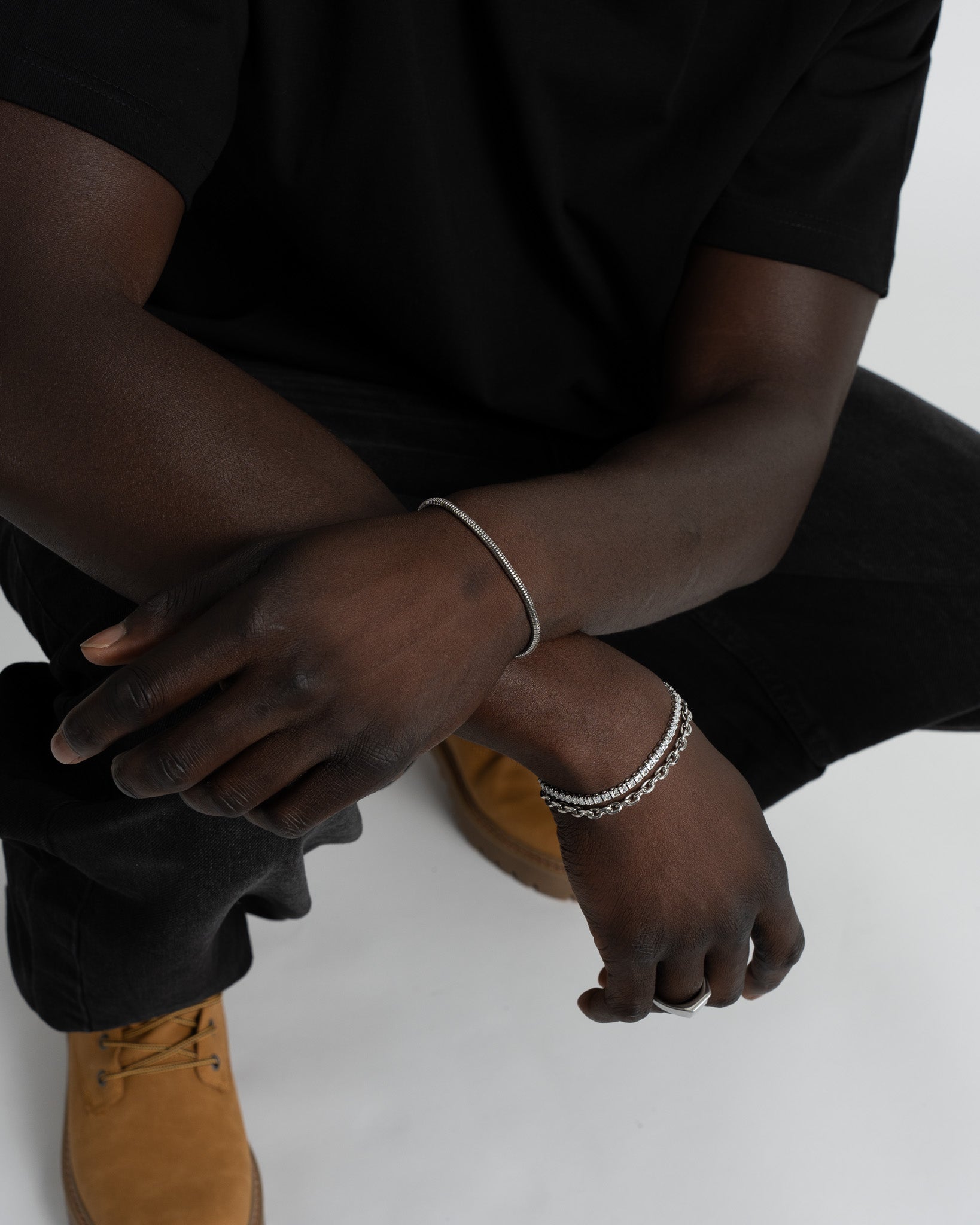 Close up of Sunset silver bracelets stacked on the wrist showing the stone band and chain link