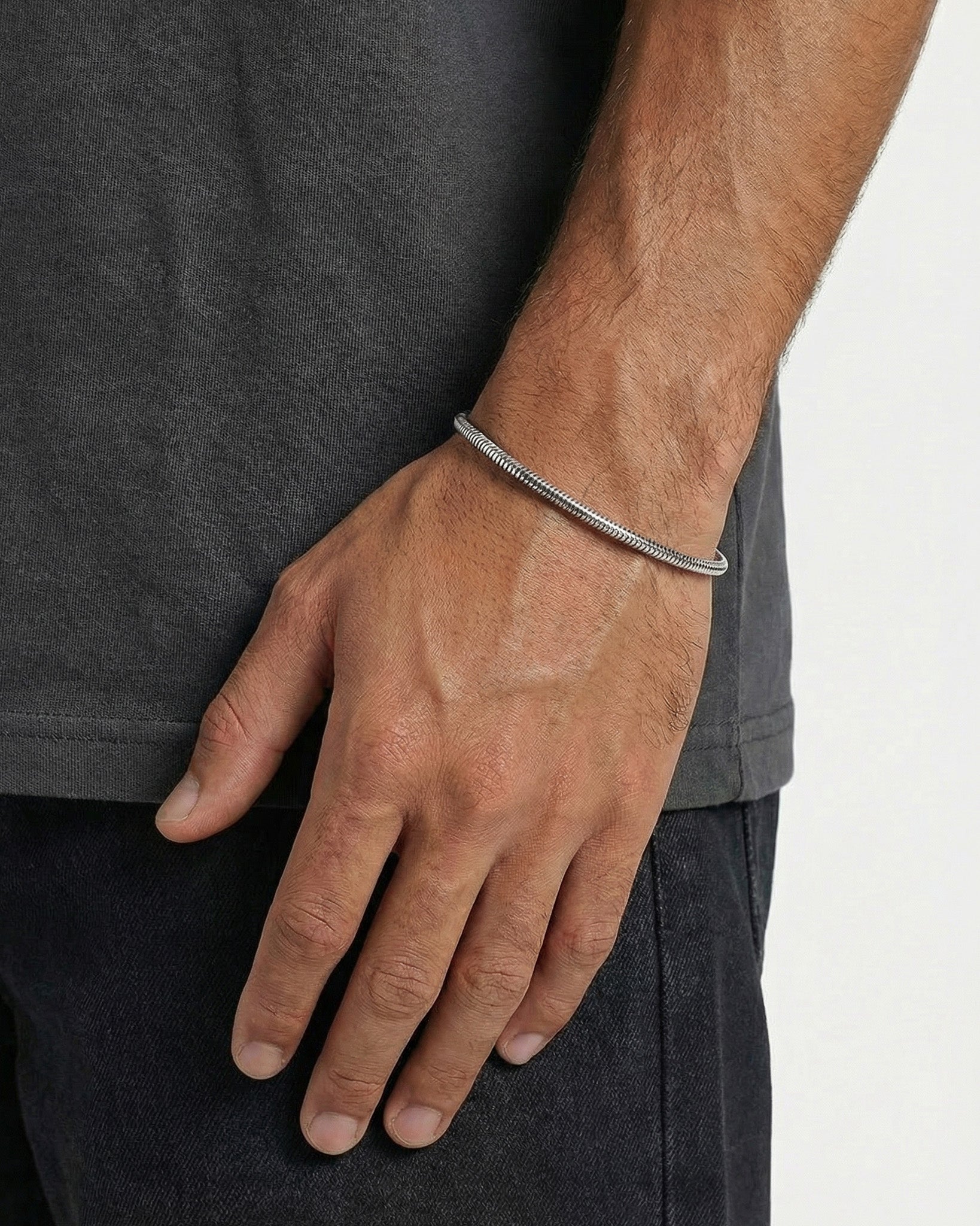 Close-up of a Sunset Silver Bracelet worn on a man's wrist against dark clothing.