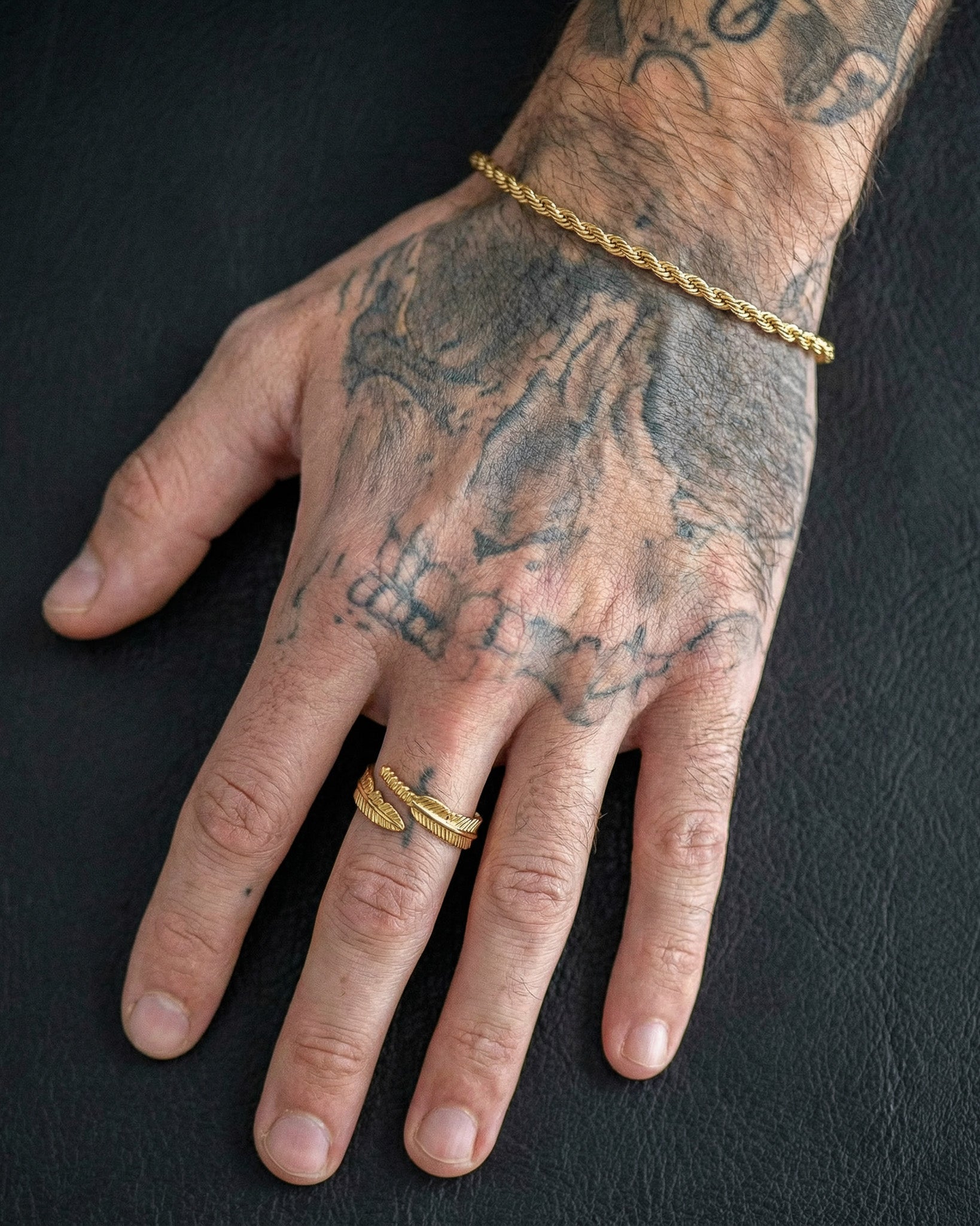Tattooed hand wearing a gold rope bracelet and Tahoe Gold Ring