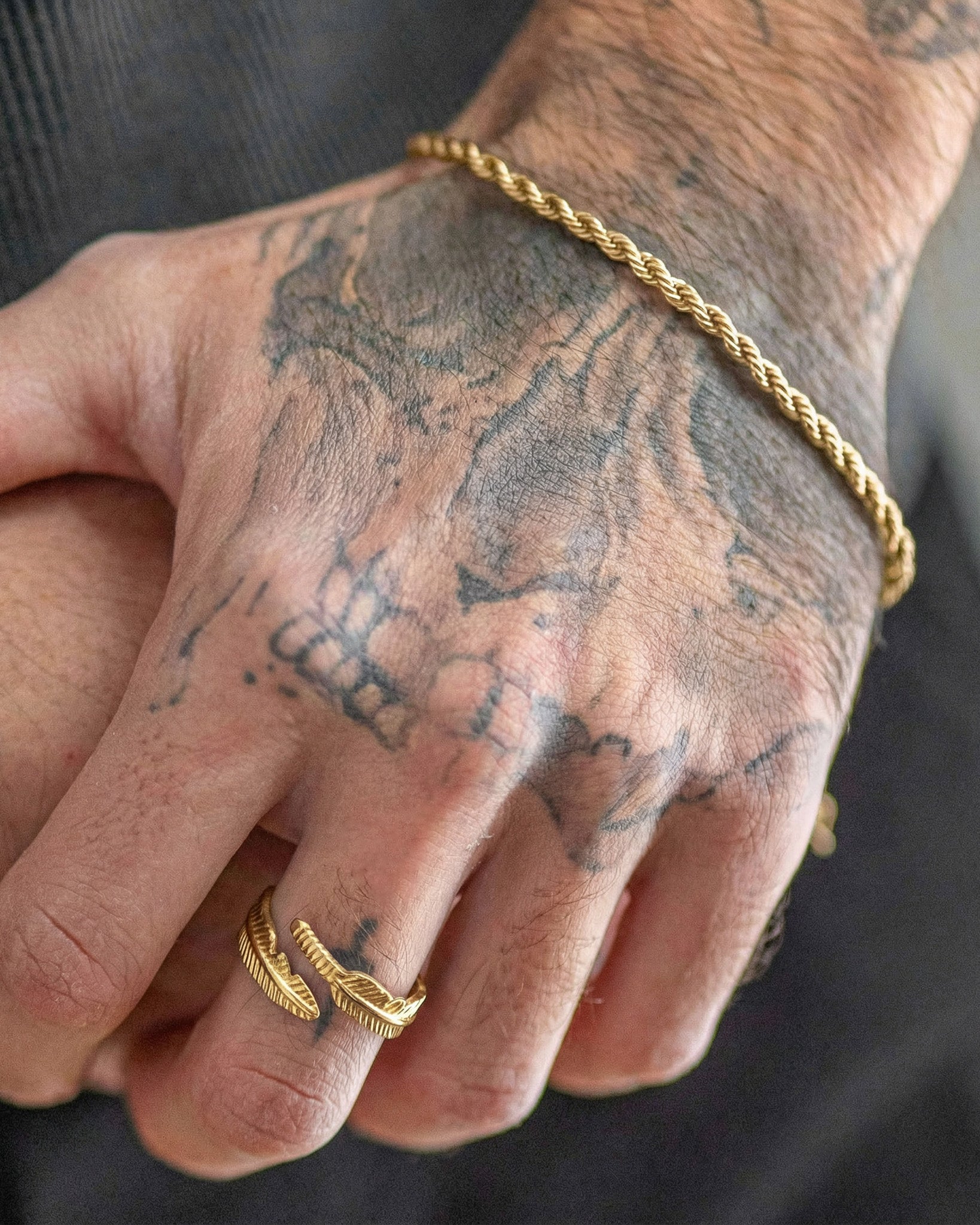 Gold rope bracelet worn on a tattooed wrist