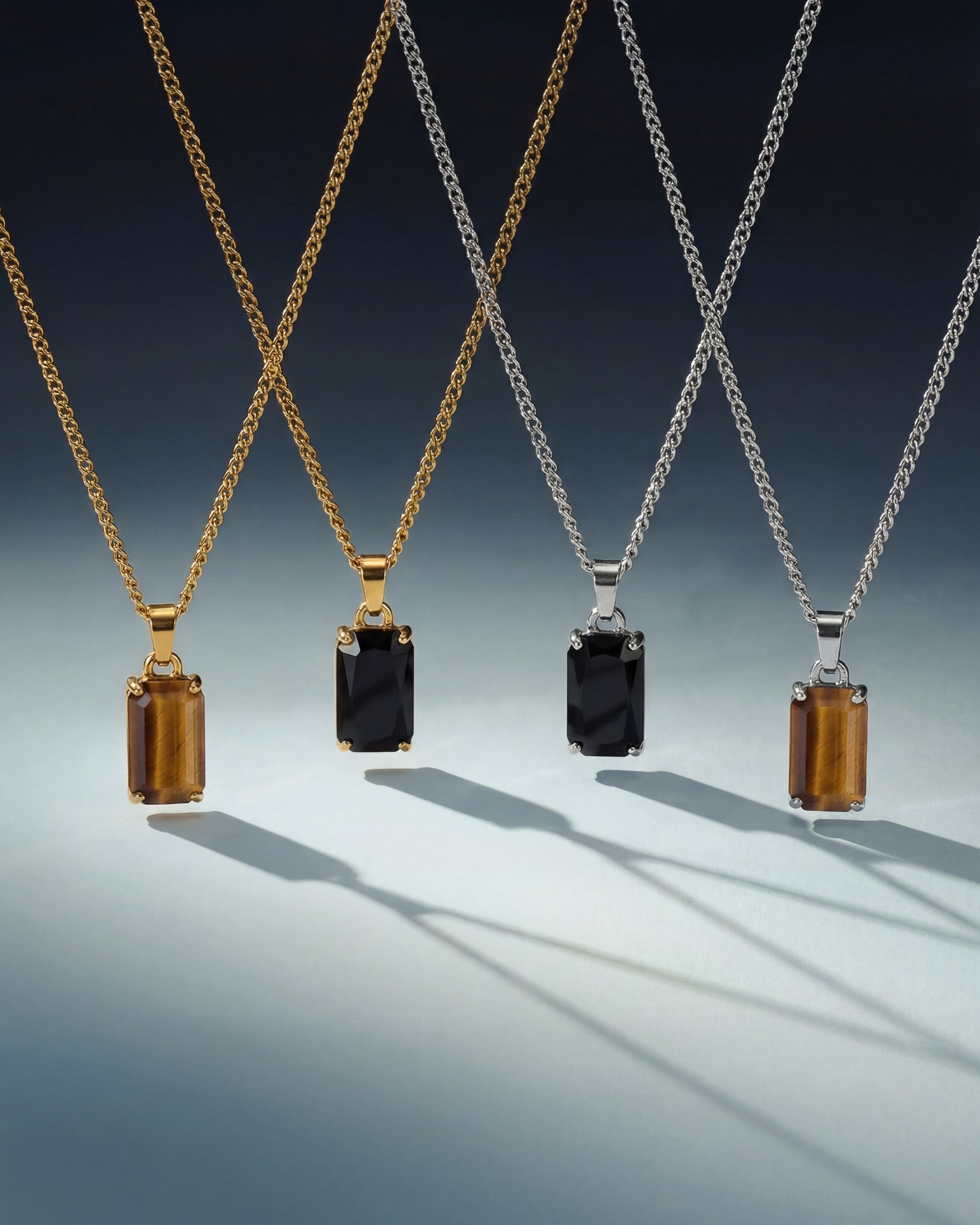 Assorted VOLT necklaces in gold and silver tones with bold rectangular gemstone pendants on a gradient backdrop