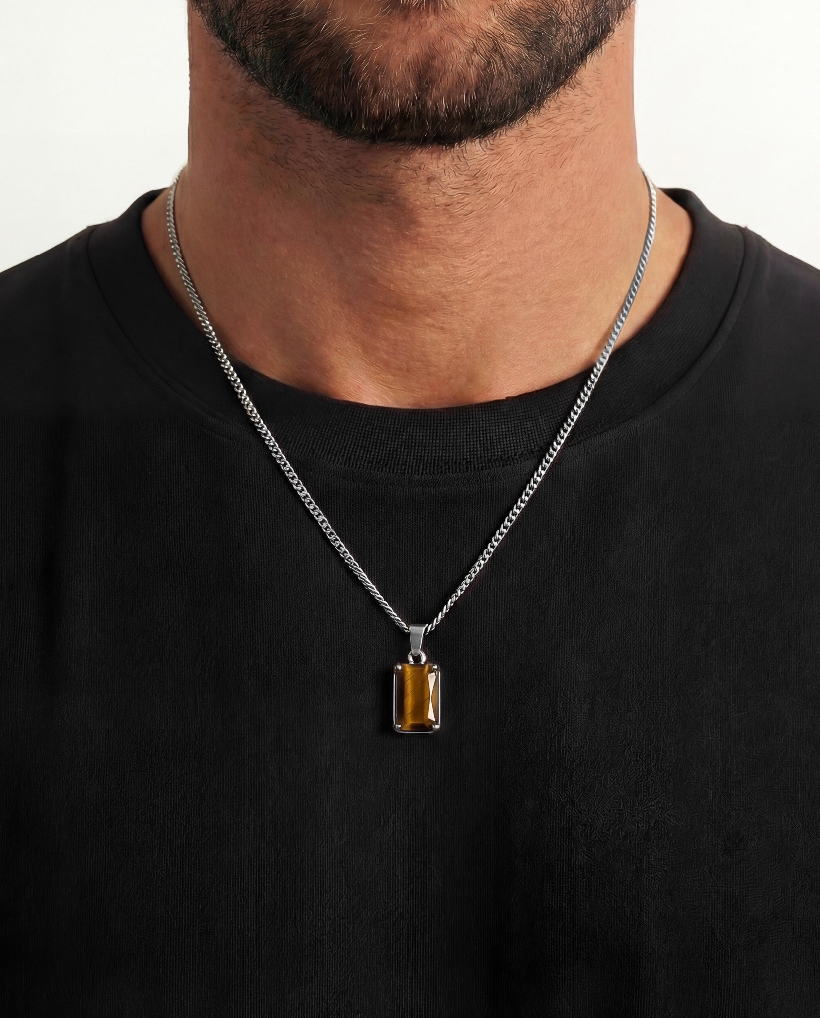 Silver VOLT necklace worn by a man with a tiger eye pendant against a black shirt